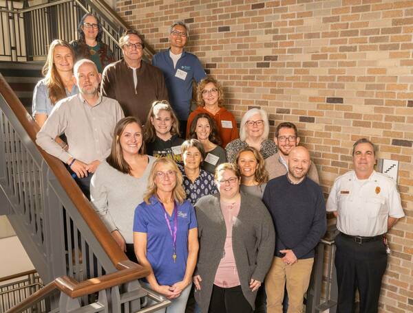 The attendees of the NDSI and Community Partners meeting stand on a staircase smiling